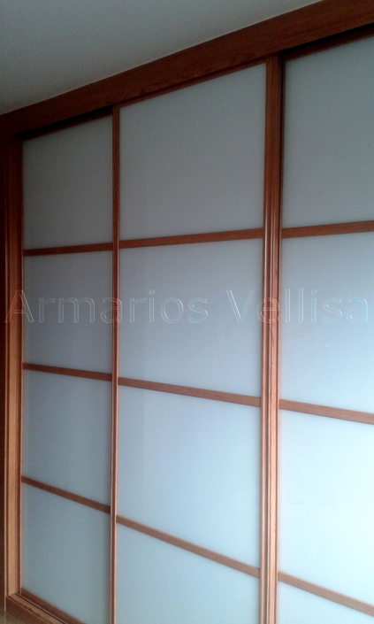 Armario a medida en dormitorio. Puertas correderas: 3 Modelo Japonés con 3 junquillos horizontales por puerta sobre cristal blanco. Color base: Cerezo melamina